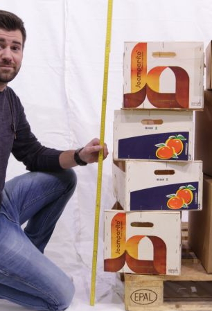 Mitarbeiter hält Zollstock neben Kartons und bestimmt die Höhe
