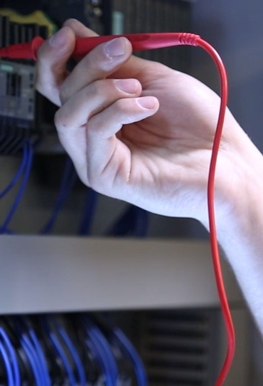 Une main tient un câble électrique