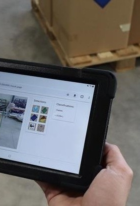 Employee holds tablet in hand and sees boxes and how Predictive Vision for Logistics works