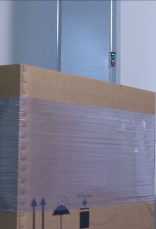 A shipping label is applied to a cardboard box using redtagger