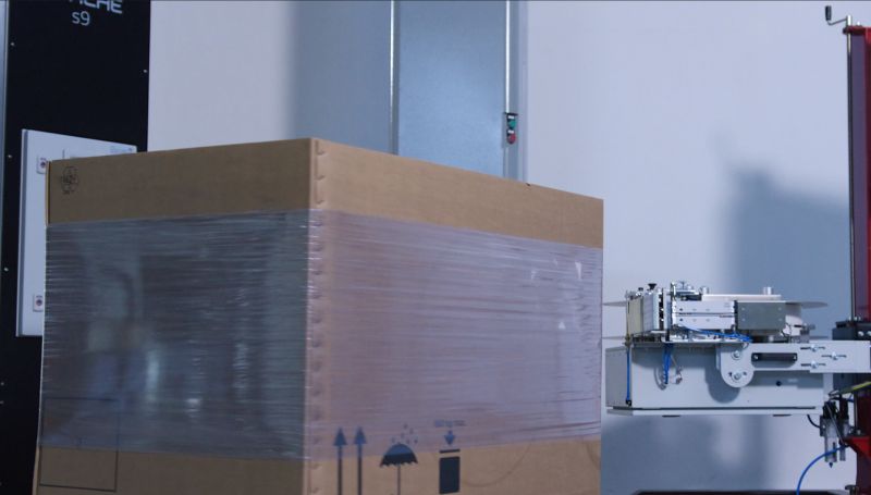 A shipping label is applied to a cardboard box using redtagger